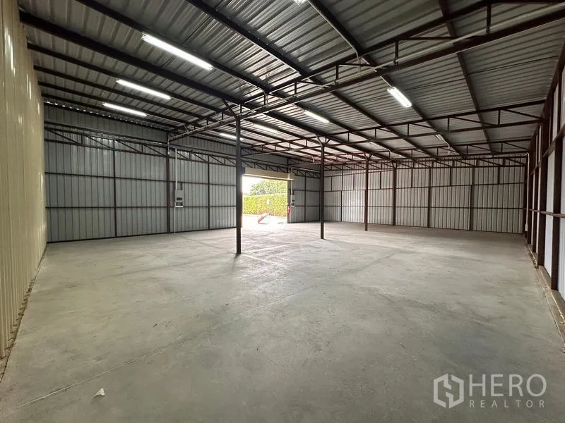 Warehouse for rent in Mueang Nonthaburi, Nonthaburi - Deep view of warehouse showing open bay, steel trusses, bright lighting, and level concrete surface.