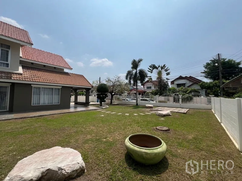 Detached House for sale in Mueang Pathum Thani, Pathum Thani - Expansive lawn and side view of the house with tiled roof and garden planter.