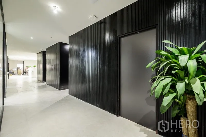 办公空间 出租或出售在Huai Khwang, Bangkok - 黑色质感墙面的走廊，点缀绿色盆栽。