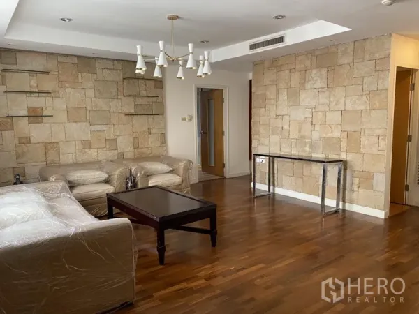 公寓 出租或出售在Sathon, Bangkok - 宽敞客厅，石纹特色墙、吊灯、沙发与茶几，木地板