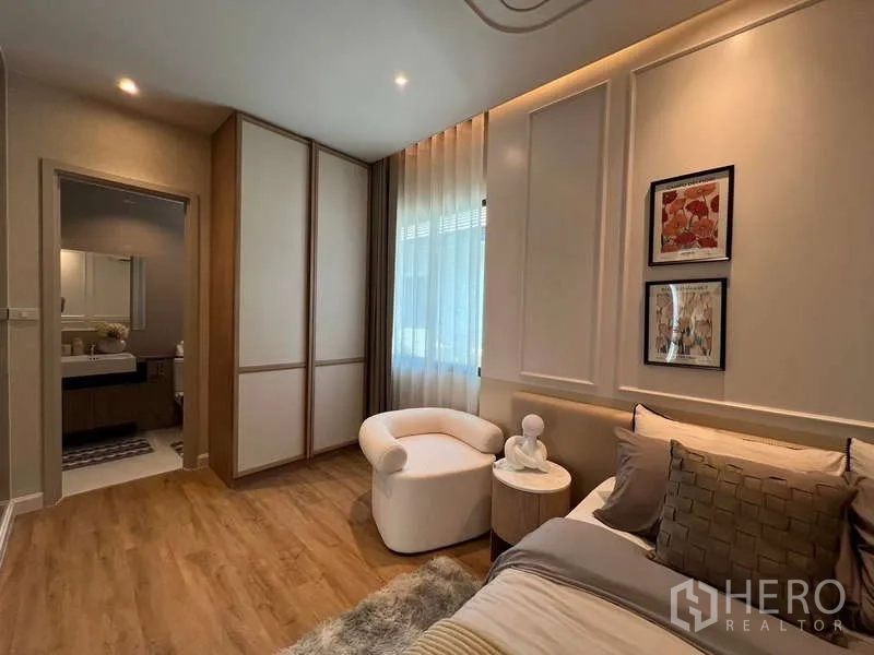 Detached House for sale in Saphan Sung, Bangkok - Bedroom corner with reading chair, built-in wardrobes and door to bathroom.