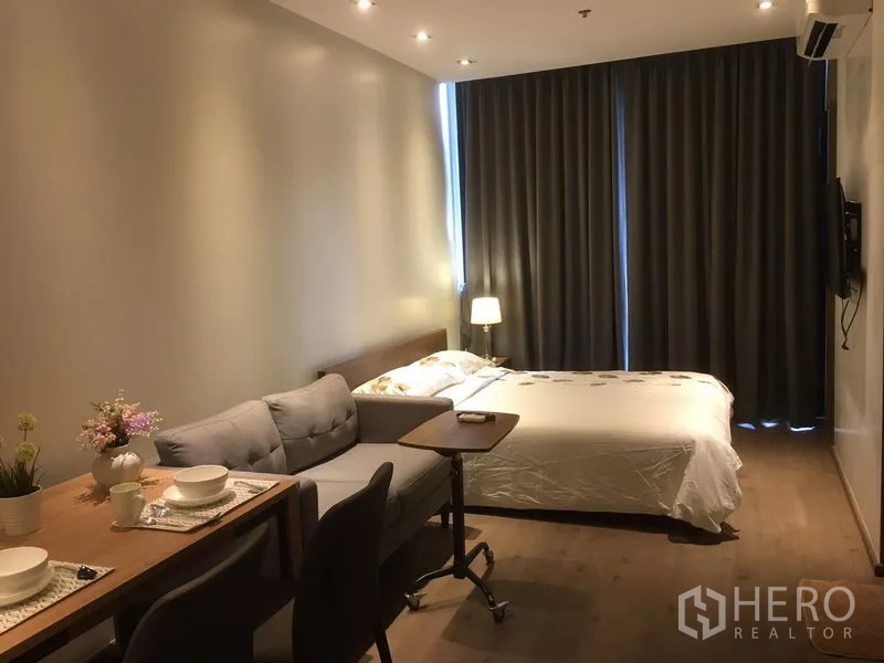 คอนโด ให้เช่าในKhlong Toei, Bangkok - พื้นที่นั่งเล่นแบบเปิดโล่ง มีโต๊ะทานข้าว โซฟา และเตียง พร้อมพื้นไม้และผ้าม่านสูง