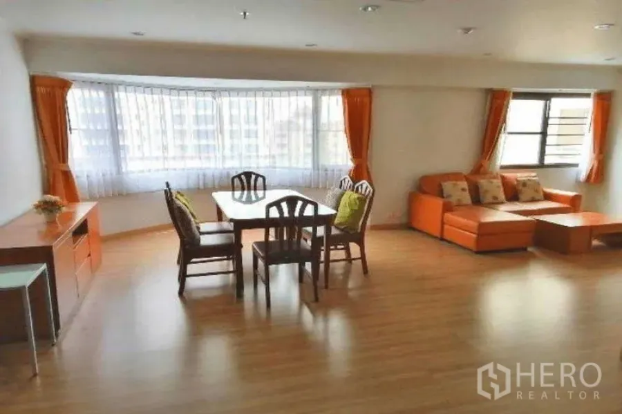 Condominium for rent in Watthana, Bangkok - Wide living and dining space with bay window bringing in light and orange drapes.