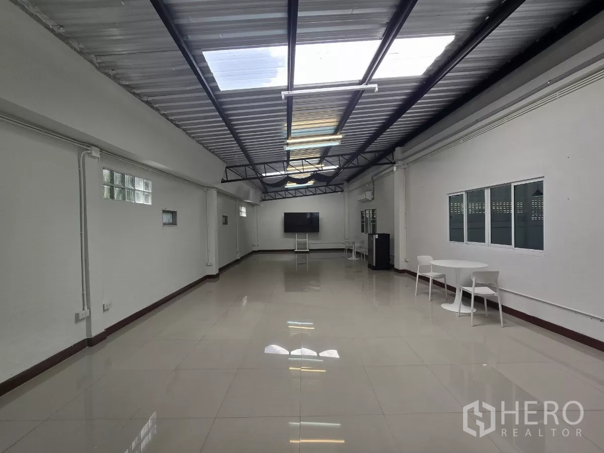 Warehouse for rent in Chatuchak, Bangkok - Second-floor office room with skylights, windows and seating.