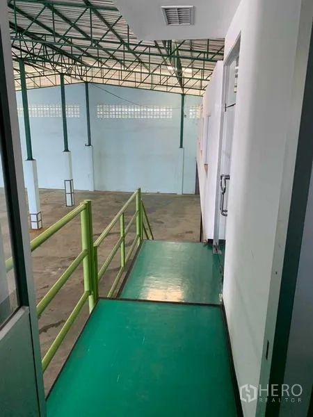คลังสินค้า ให้เช่าในBang Phli, Samut Prakan - ทางเดินชั้นลอยพร้อมราวกันตกสีเขียว มองเห็นพื้นที่โกดังเพดานสูงด้านล่าง