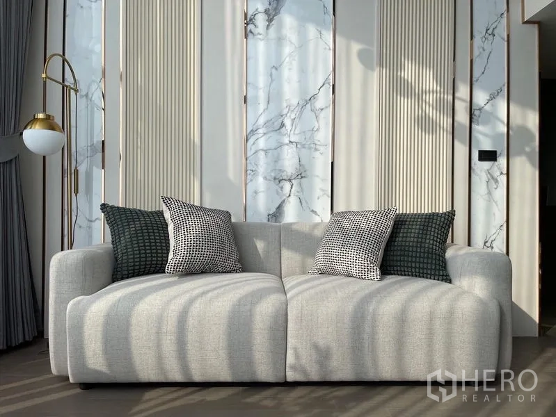 Condominium for rent - Plush light-gray sofa against marble-accent feature wall and modern floor lamp.