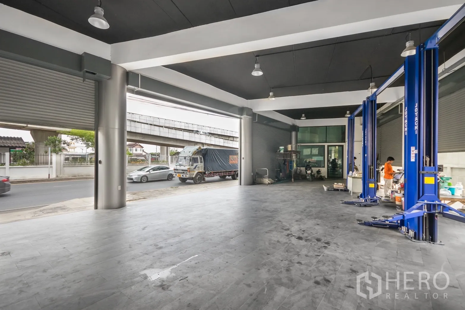 展厅 出租在Khan Na Yao, Bangkok - 一层服务区层高高、卷帘门与车辆升降设备，可直接临街通行。