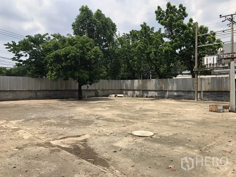 货栈 出租在Lak Si, Bangkok - 围墙内的大型混凝土院坪，树荫与电线杆，可供货车调头与停车。