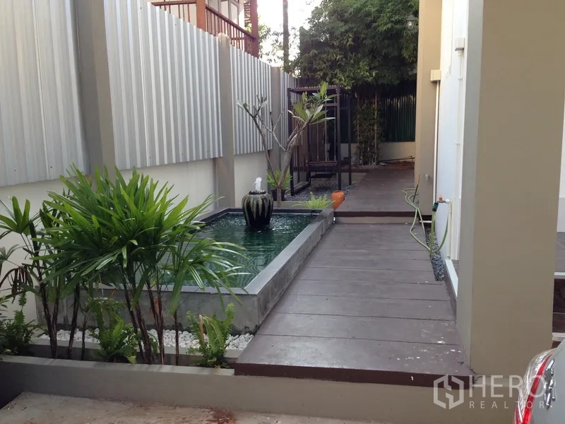 独立式住宅 出售在Phra Khanong, Bangkok - 侧院设景观水池、步道与热带植物，氛围宁静。