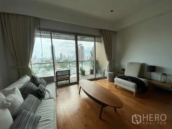 Condominium for rent in Yan Nawa, Bangkok - Living area opening to a glass-fronted balcony overlooking the Bangkok skyline.