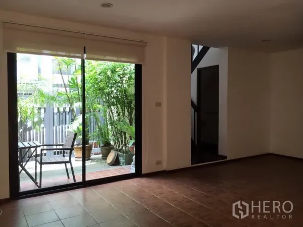 联排别墅 出租在Watthana, Bangkok - 采光客厅，落地推拉门通向小型露台花园。