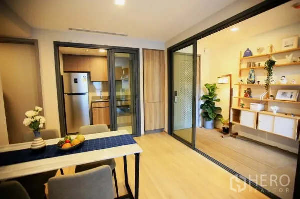 คอนโด ให้เช่าหรือขายในWatthana, Bangkok - พื้นที่รับประทานอาหารโต๊ะ 4 ที่นั่ง มองเห็นครัวปิดพร้อมตู้เย็นสแตนเลส และประตูกระจกไปยังห้องกระจกอเนกประสงค์