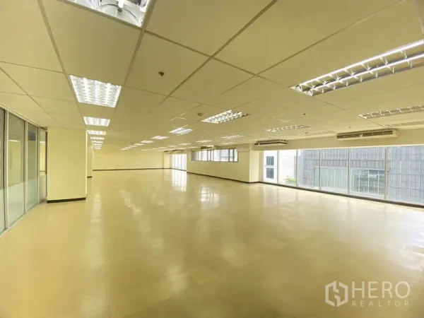 办公空间 出租在Watthana, Bangkok - 大型空置办公楼层，格栅吊顶、空调机组与转角窗。