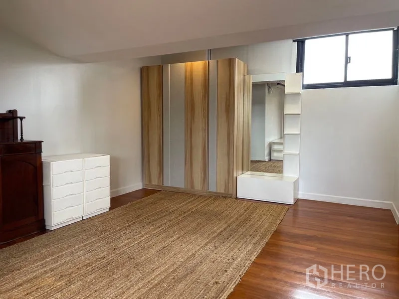 Townhouse for rent in Khlong Toei, Bangkok - Flexible room with wardrobes, full-length mirror and woven rug.