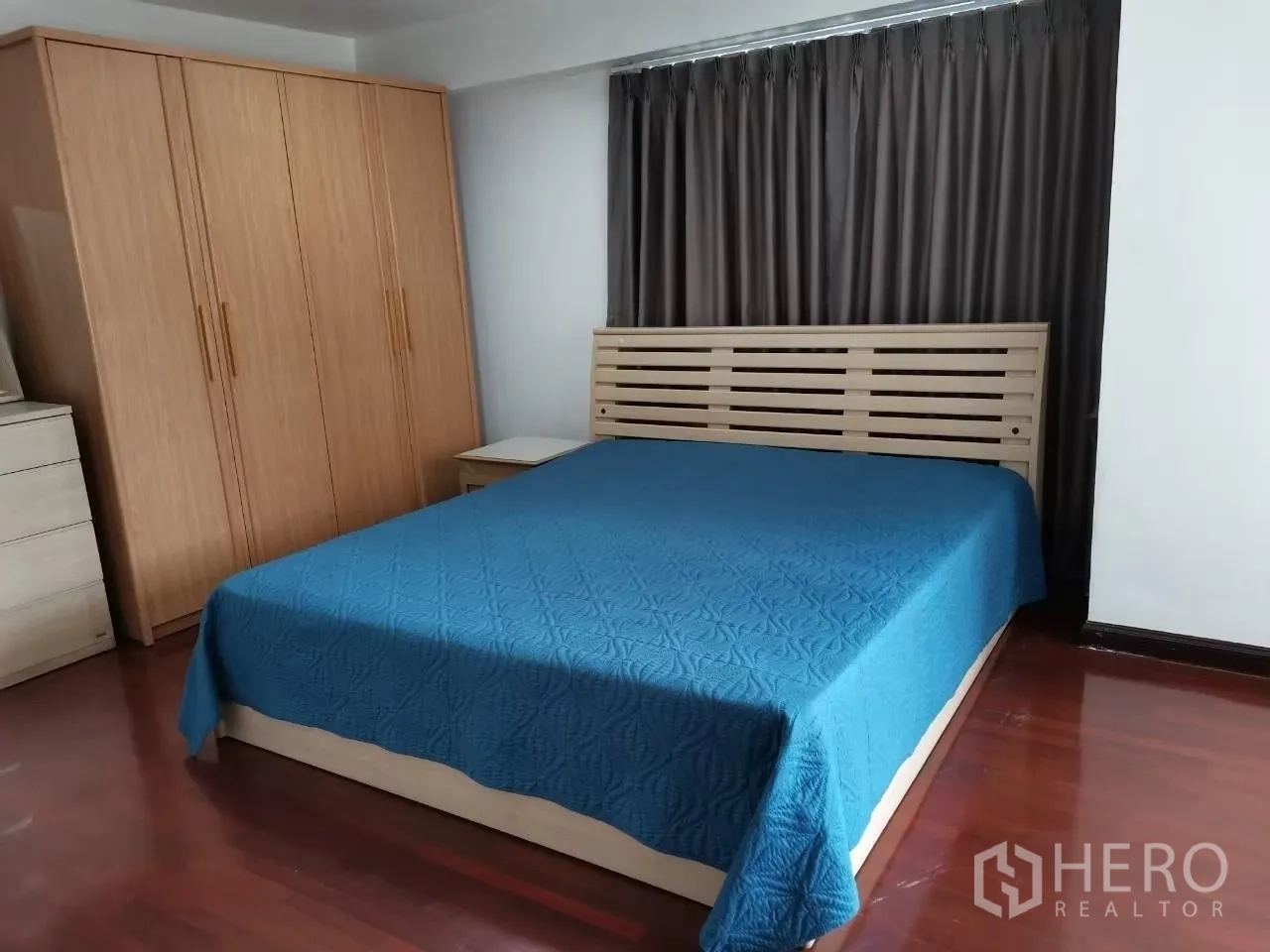 คอนโด ให้เช่าในPhaya Thai, Bangkok - ห้องนอนพร้อมผ้าคลุมเตียงสีน้ำเงิน ตู้เสื้อผ้าไม้ โต๊ะข้างเตียง และผ้าม่านทึบ