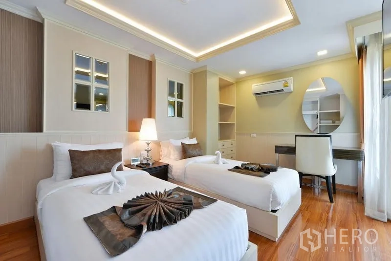 Apartment for rent in Khlong Toei, Bangkok - Twin bedroom with desk, shelving, air conditioner and warm wood flooring.