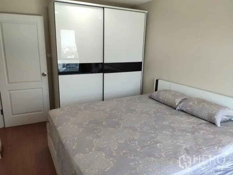 Condominium for rent in Huai Khwang, Bangkok - Master bedroom with king bed and sleek sliding-door wardrobe in white and black.
