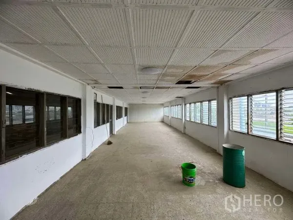 工厂 出租在Sai Noi, Nonthaburi - 空置办公走道，双侧百叶窗，吊顶与水泥地面。