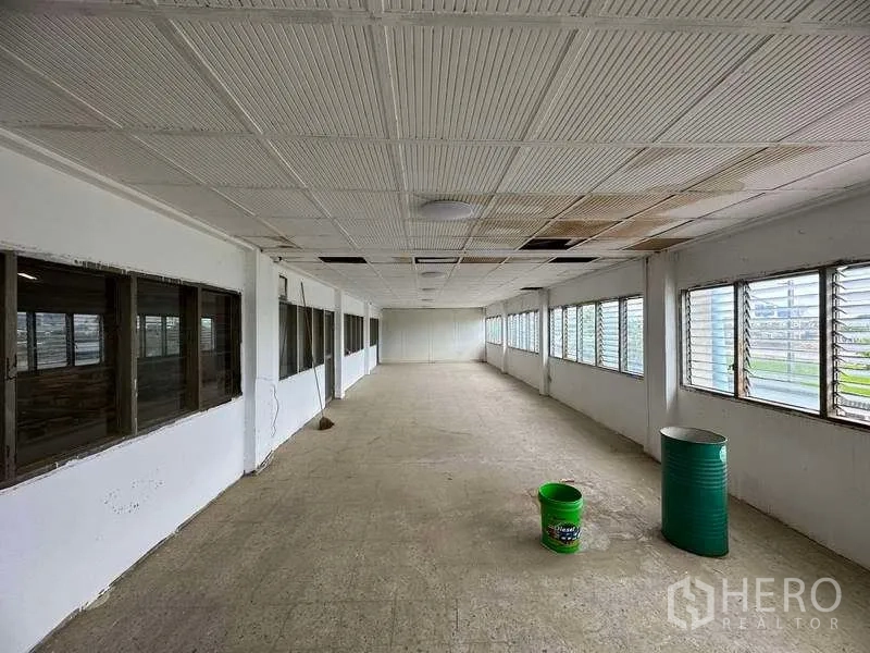 工厂 出租在Sai Noi, Nonthaburi - 空置办公走道，双侧百叶窗，吊顶与水泥地面。