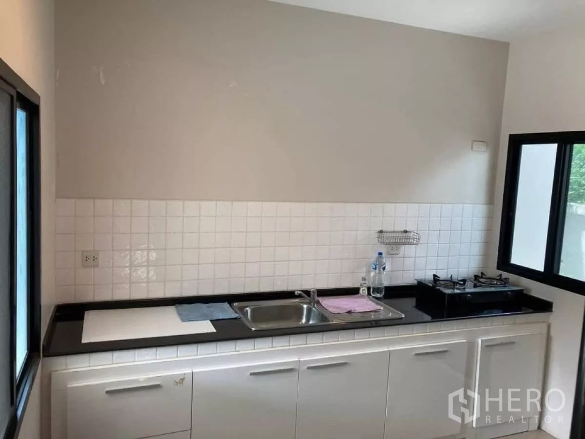 บ้าน ให้เช่าในMueang Nonthaburi, Nonthaburi - ครัวปิดตู้บิวท์อินสีขาว อ่างล้างจาน และเตาแก๊สติดริมหน้าต่าง