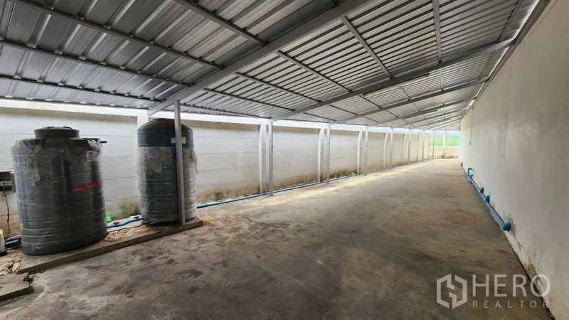 Factory for rent in Samut Sakhon - Covered side service yard with water tanks and concrete floor.