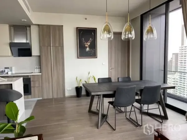 คอนโด ให้เช่าหรือขายในWatthana, Bangkok - มุมรับประทานอาหารแขวนโคมไฟดีไซน์ ข้างประตูกระจกออกสู่ระเบียง เชื่อมครัวแบบโอเพ่นพร้อมวิวเมือง