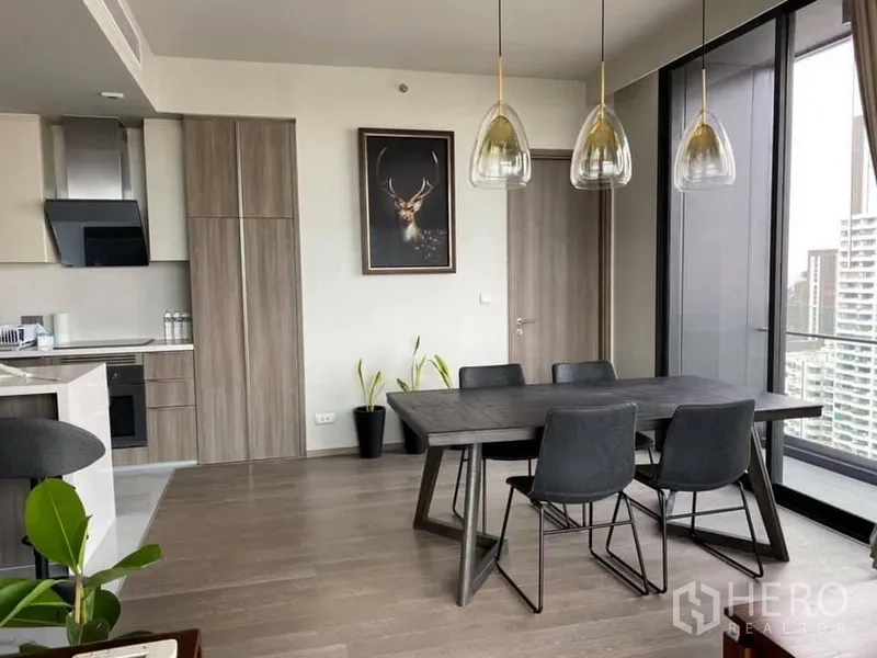 คอนโด ให้เช่าหรือขายในWatthana, Bangkok - มุมรับประทานอาหารแขวนโคมไฟดีไซน์ ข้างประตูกระจกออกสู่ระเบียง เชื่อมครัวแบบโอเพ่นพร้อมวิวเมือง