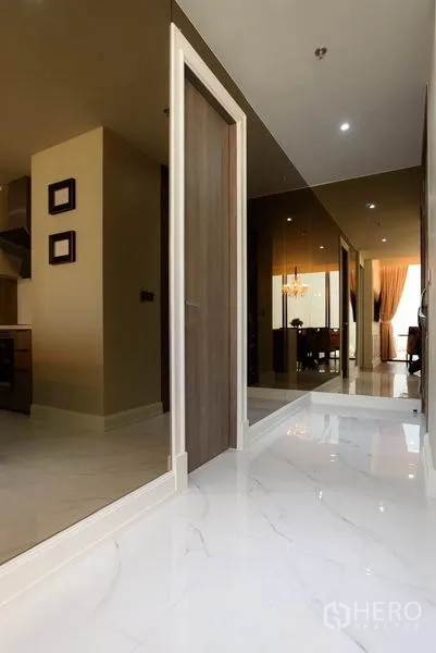 Condominium for rent or sale in Watthana, Bangkok - Entry hallway with reflective wall panels, white marble floor leading to dining area.