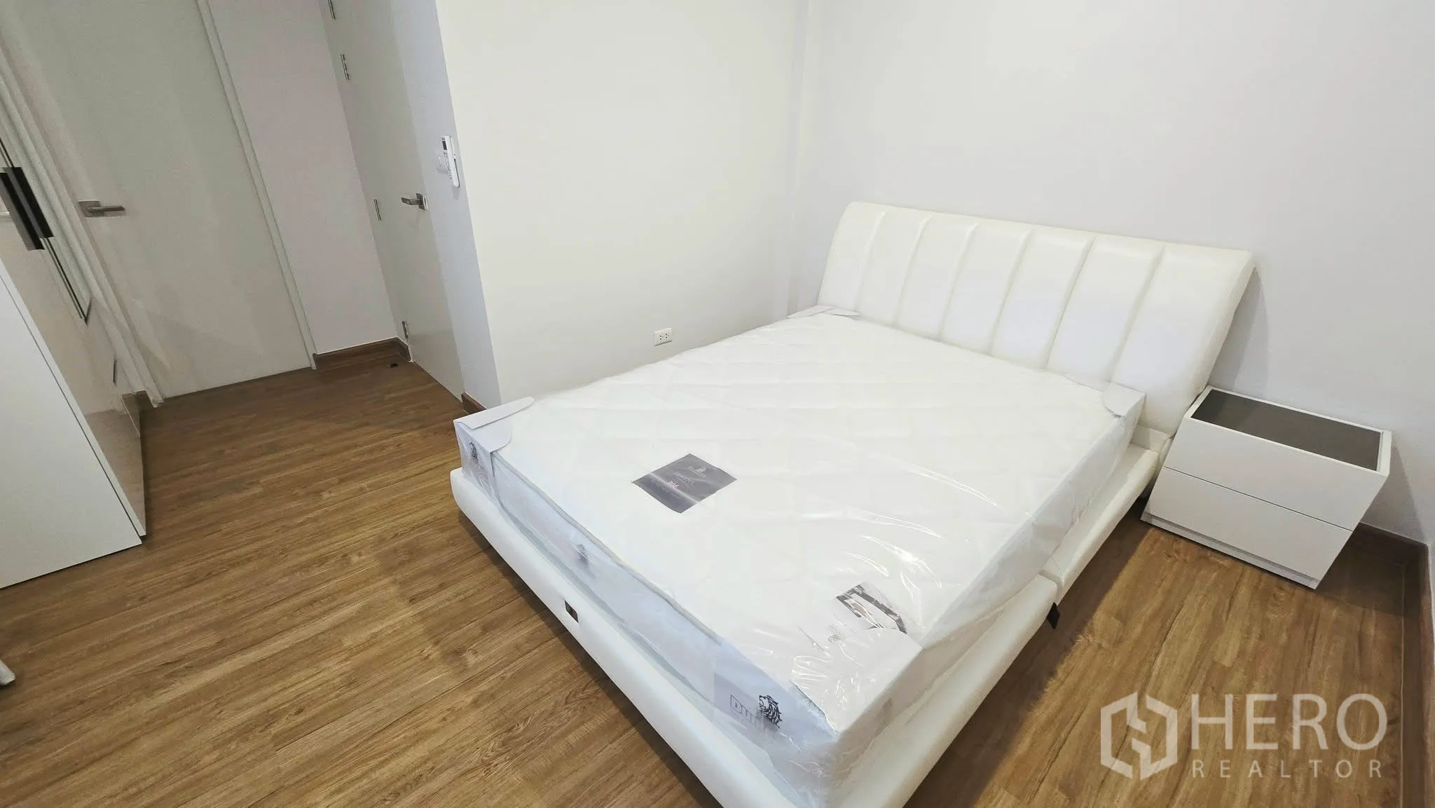 Detached House for rent in Prawet, Bangkok - Guest bedroom with white upholstered bed and wood flooring.