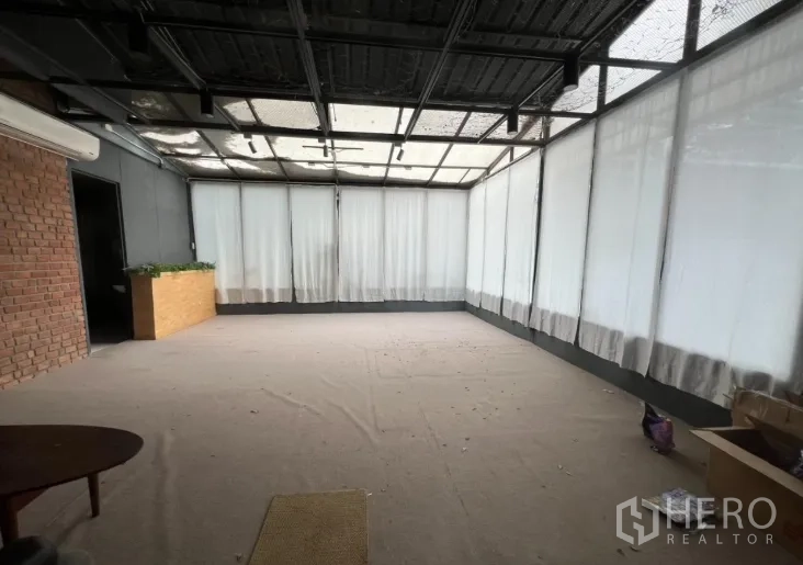 零售空间 出租在Watthana, Bangkok - 开放式室内，玻璃顶与环窗窗帘，旁有红砖装饰墙。