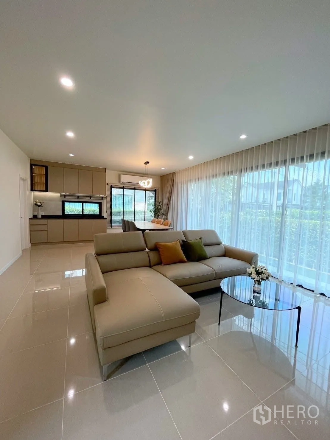 Detached House for rent in Bang Phli, Samut Prakan - Open-plan living area with sectional sofa and glass coffee table facing greenery outside.
