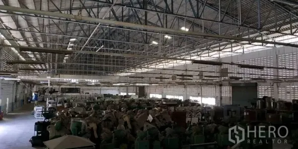Factory for rent in Chachoengsao - Spacious warehouse interior with a high steel truss roof, skylights, and equipment storage.