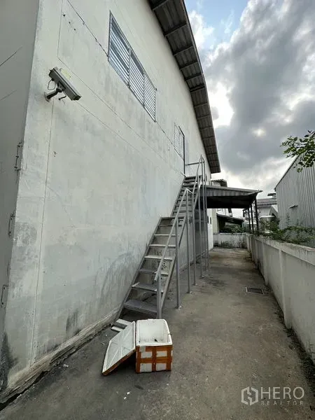 工厂 出租在Bang Bua Thong, Nonthaburi - 仓库外墙沿线的金属楼梯，后侧服务通道与安防灯