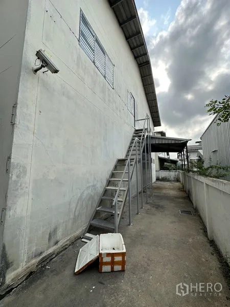 工厂 出租在Bang Bua Thong, Nonthaburi - 仓库外墙沿线的金属楼梯，后侧服务通道与安防灯