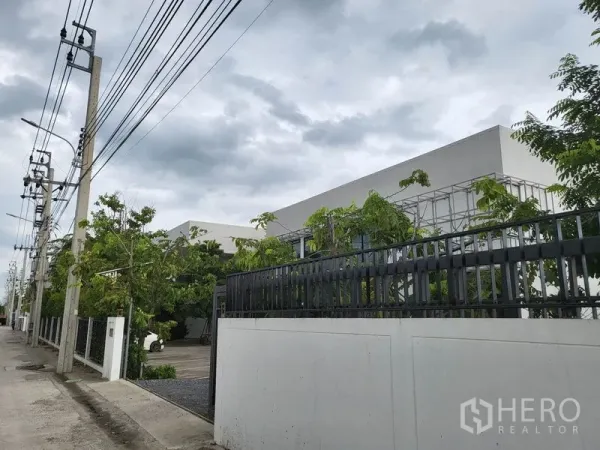 คลังสินค้า ขายในLat Krabang, Bangkok - ภาพจากถนน รั้วเหล็กและเสาไฟฟ้าหน้าโครงการโกดัง