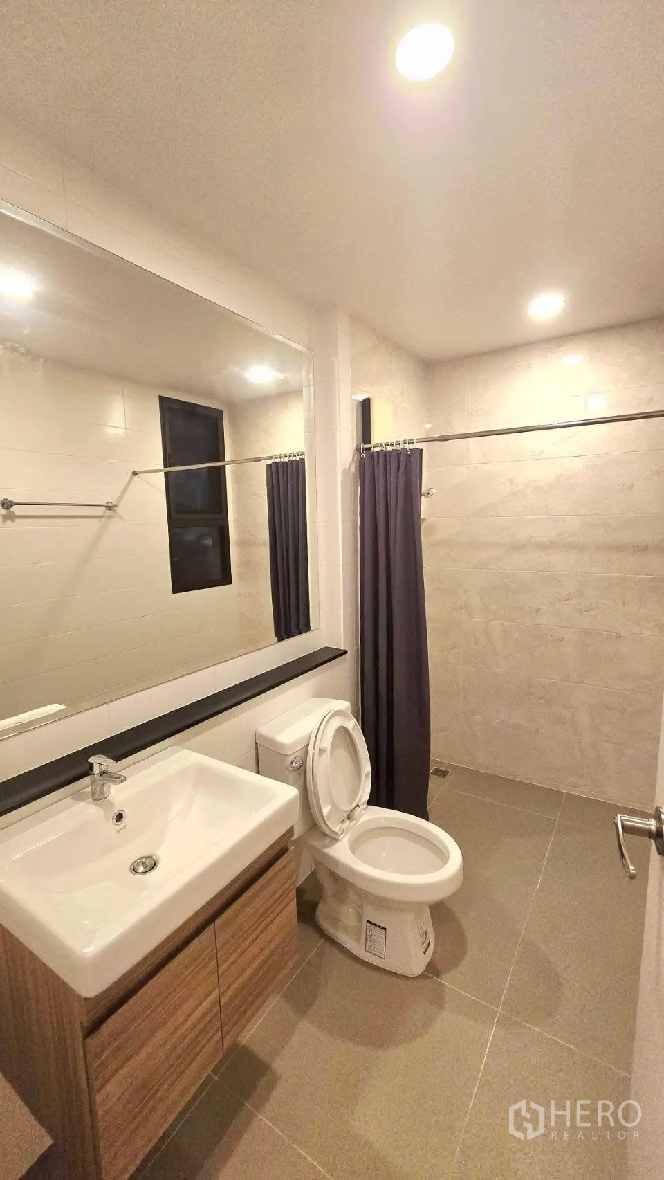 Detached House for rent in Prawet, Bangkok - Bathroom with vanity, toilet and a walk-in shower area with curtain and beige tiles.