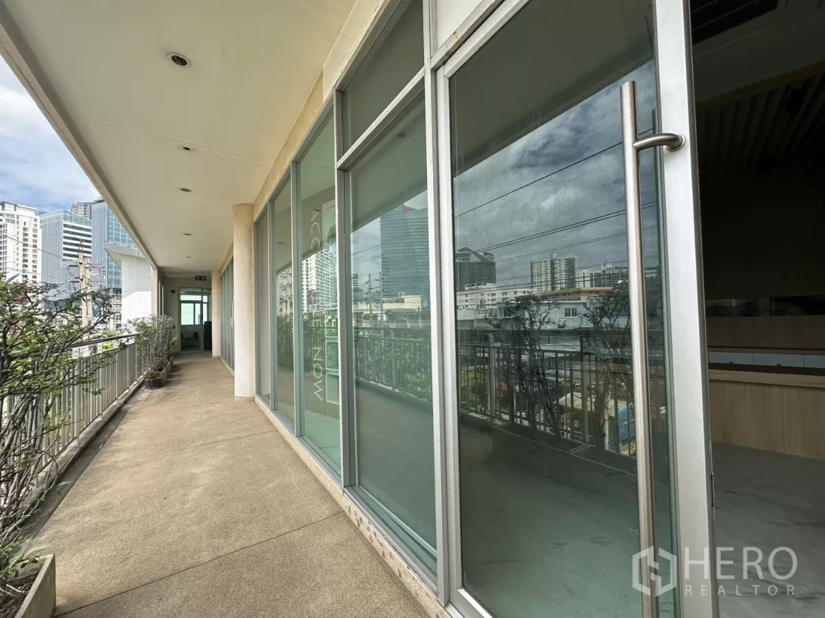 零售空间 出租在Phra Khanong, Bangkok - 开放走道旁的玻璃门店入口，可见城市天际线。