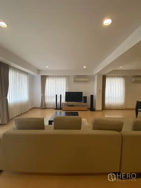 อพาร์ทเมนท์ ให้เช่าในWatthana, Bangkok - ห้องนั่งเล่นสว่างด้วยหน้าต่างหลายด้าน ผ้าม่านโปร่ง และชั้นวางทีวีตรงข้ามโซฟา.