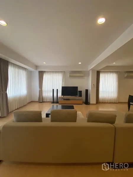 อพาร์ทเมนท์ ให้เช่าในWatthana, Bangkok - ห้องนั่งเล่นสว่างด้วยหน้าต่างหลายด้าน ผ้าม่านโปร่ง และชั้นวางทีวีตรงข้ามโซฟา.