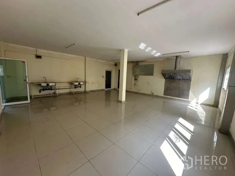 Home Office for rent in Chatuchak, Bangkok - Empty commercial prep room with tiled floor, sinks and large exhaust hood.