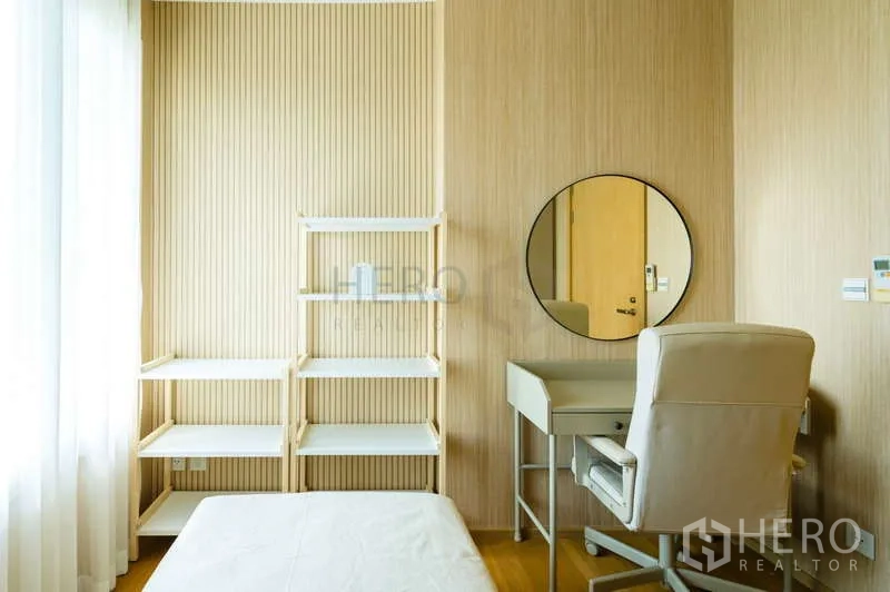 Condominium for sale in Khlong Toei, Bangkok - Workstation with round mirror and shelving in a bright secondary bedroom.