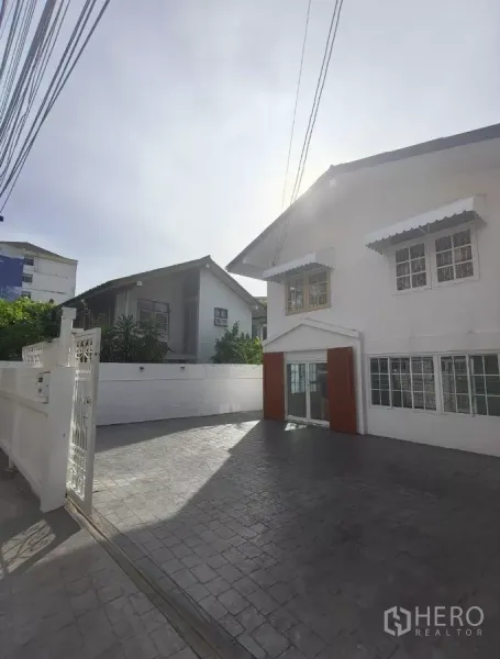 Detached House for rent in Bang Na, Bangkok - Gated entrance and spacious paved parking area in front of the detached house with white boundary walls.