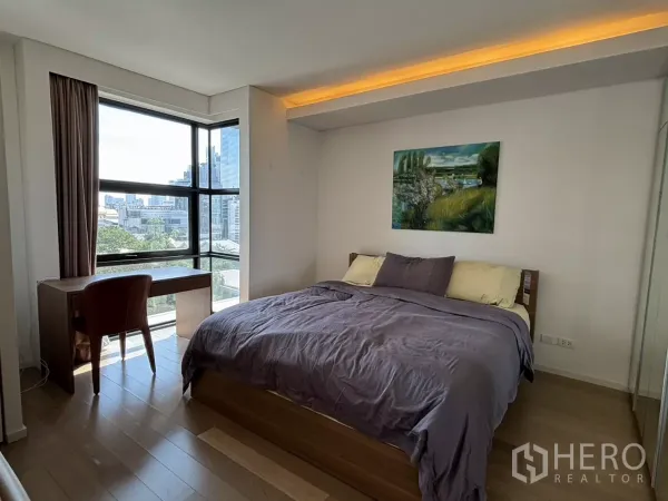 Condominium for sale in Watthana, Bangkok - Corner bedroom with large windows, double bed, and study desk overlooking the skyline.