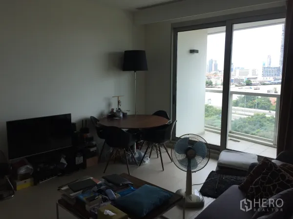 Condominium for rent or sale in Khlong San, Bangkok - Bright living area with sliding glass doors to a balcony and city skyline view in Khlong San, Bangkok.