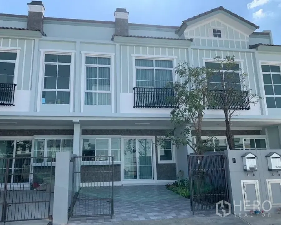 联排别墅 出租 - Indy 2 社区两层联排别墅外立面，带栅栏车位与阳台栏杆。