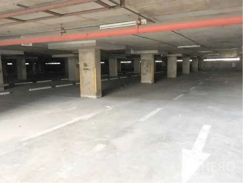 Warehouse for rent in Khlong Toei, Bangkok - Covered parking level with marked bays and concrete pillars in the complex.