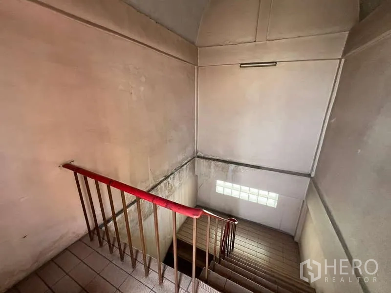 店屋 出租 - 室内楼梯间，红色扶手与高挑墙面。