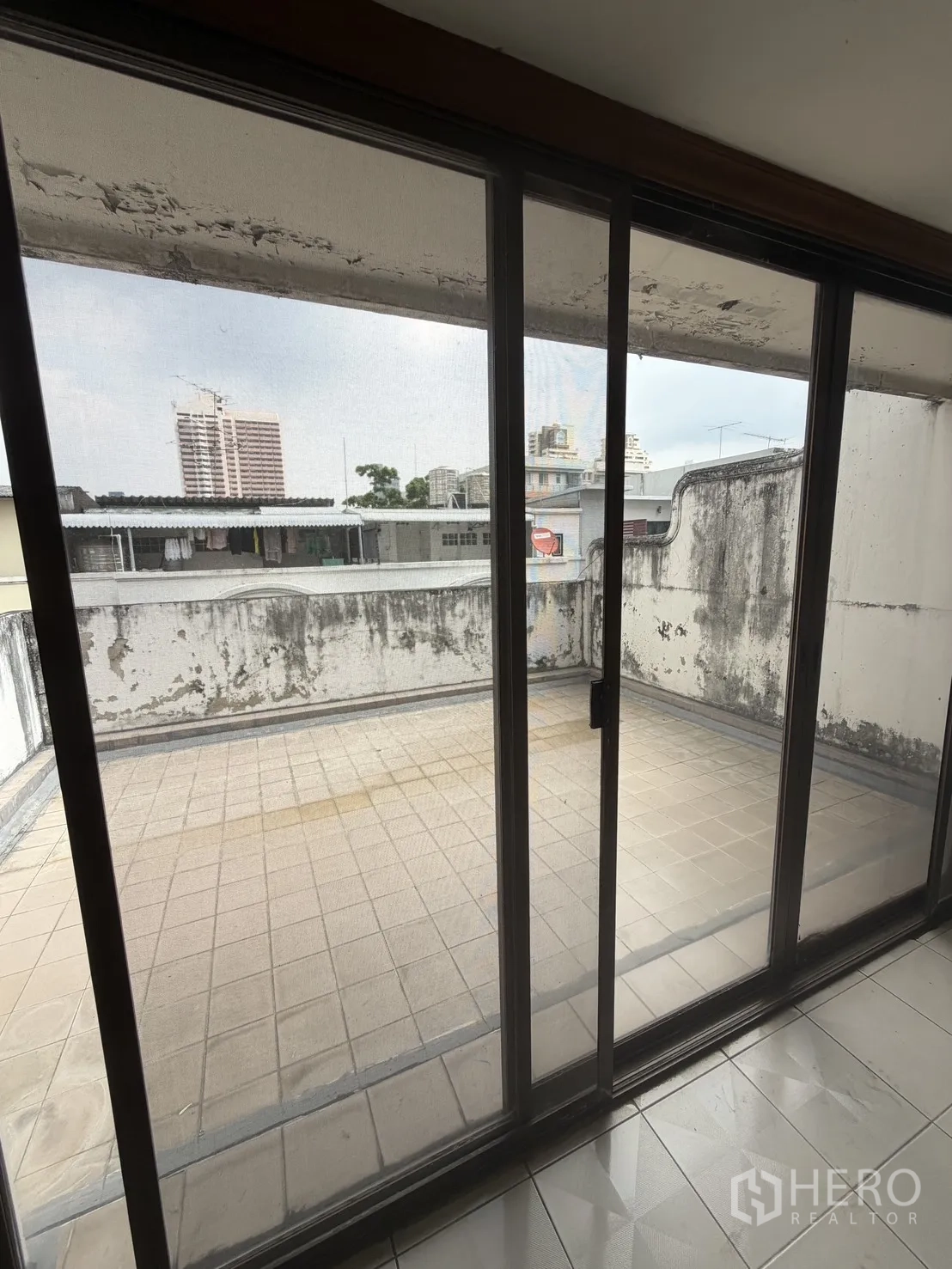 Home Office for rent in Watthana, Bangkok - Large tiled terrace viewed through sliding glass doors with city outlook.