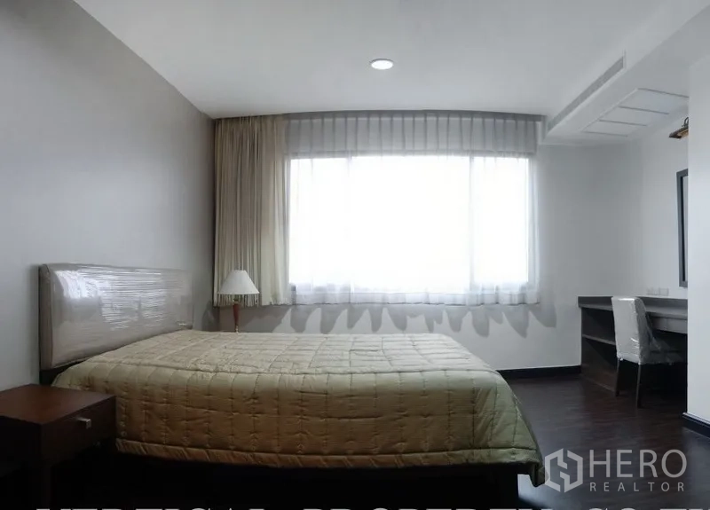 Condominium for rent in Watthana, Bangkok - Bedroom with large window, desk, and neutral decor.