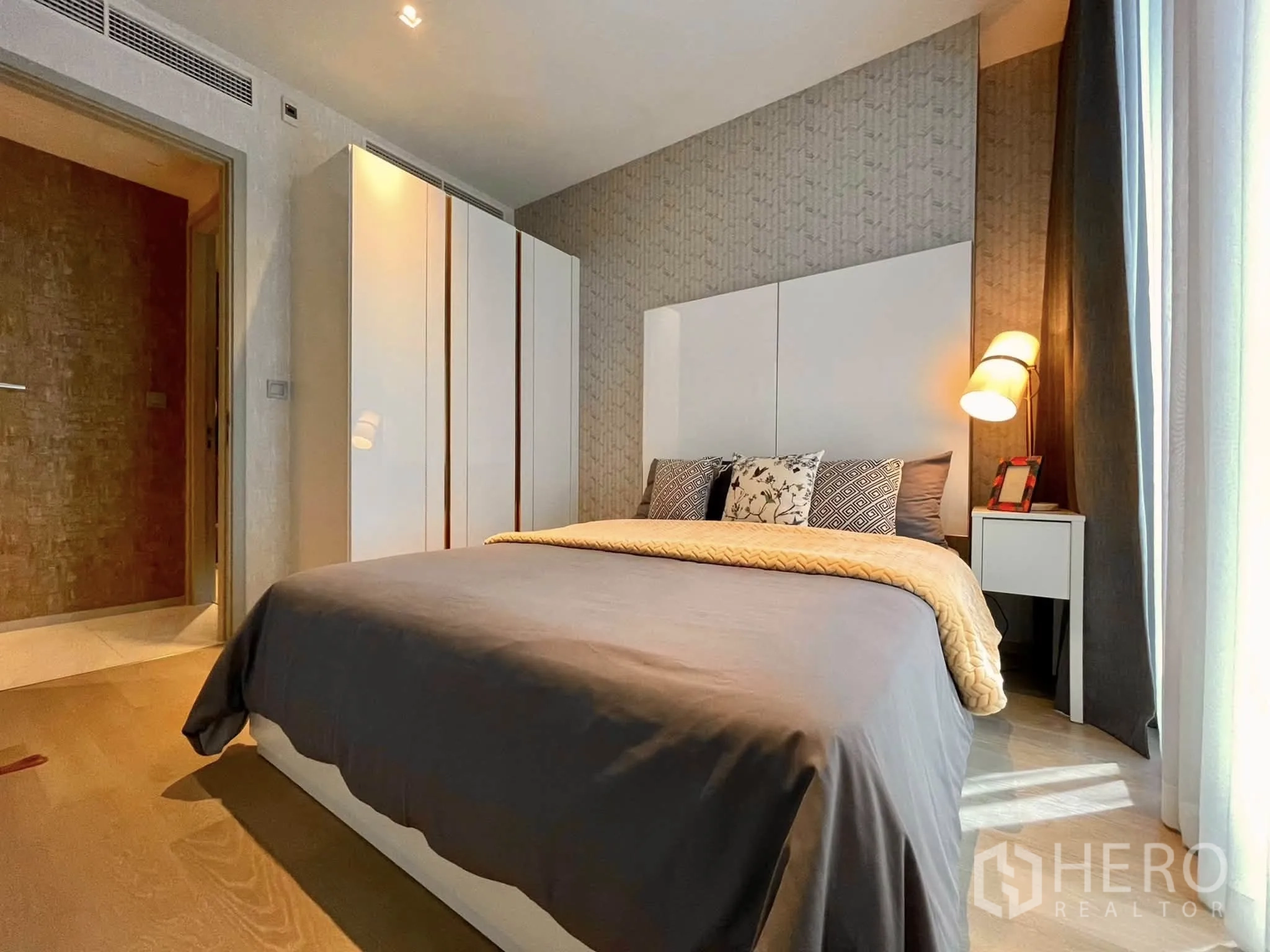 Condominium for rent in Bang Rak, Bangkok - Light-filled bedroom with bed, nightstand and tall wardrobe.